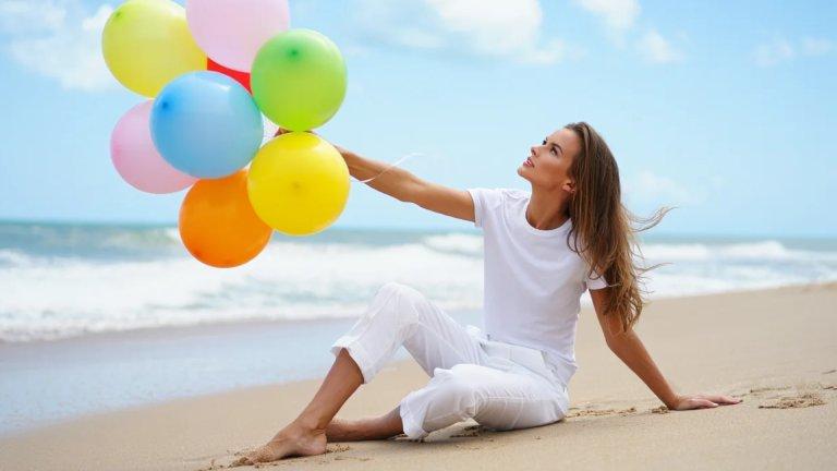 Vrouw met kleurrijke ballonnen op het strand: weer lichter na stress en burn-out, voor cliënten uit Herentals