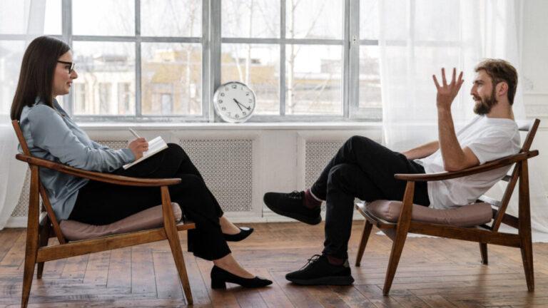 Psychotherapeut en volwassen cliënt in gesprek in een lichte praktijkruimte – gesprekstherapie in Heist-op-den-Berg