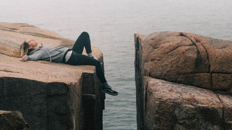 Vrouw ligt ontspannen op een rots aan het water – diepe ontspanning met Da Silva alfatraining